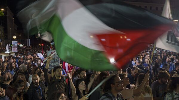 Estudiantes ondean banderas palestinas mientras participan en una protesta, el 13 de mayo, 2024 - Sputnik Mundo