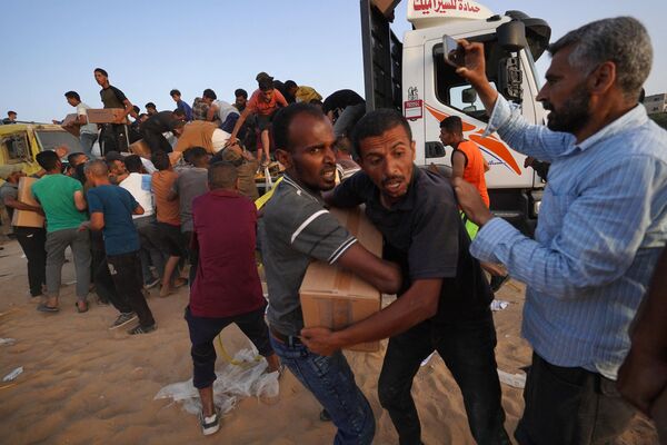Un grupo de palestinos descargando cajas de ayuda humanitaria, Palestina. - Sputnik Mundo