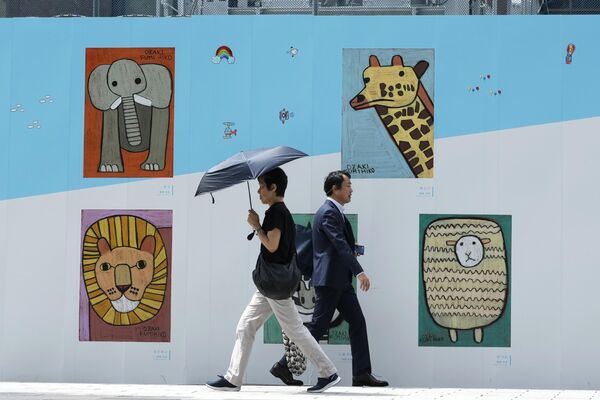 Un grupo de personas caminando delante de un muro de obras de arte colocado en el exterior de una construcción en Tokio, Japón. - Sputnik Mundo