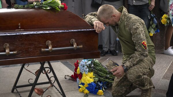 Un militar ucraniano rinde homenaje ante el ataúd de su compañero  - Sputnik Mundo