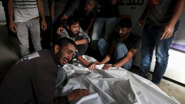 Palestinos lloran sobre los cuerpos de familiares muertos en un ataque aéreo israelí, en una morgue en Rafah, Franja de Gaza, el 27 de mayo de 2024. - Sputnik Mundo