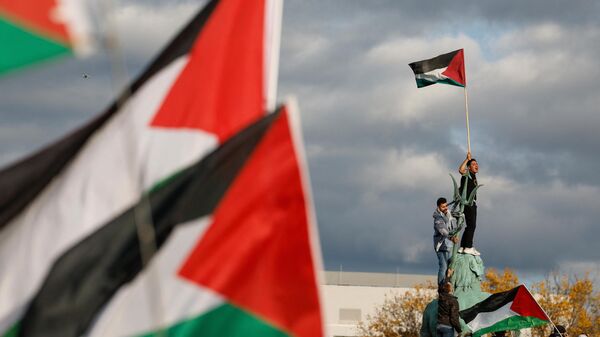 Un manifestante ondea la bandera palestina mientras se encuentra en la Fuente de Neptuno durante una protesta en apoyo a los palestinos bajo el lema 'Palestina libre' en Berlín, Alemania, el 4 de noviembre de 2023 - Sputnik Mundo
