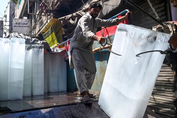 Unos obreros cargan bloques de hielo en un vehículo en plena ola de calor en la ciudad pakistaní de Lahore, el 30 de mayo de 2024. - Sputnik Mundo