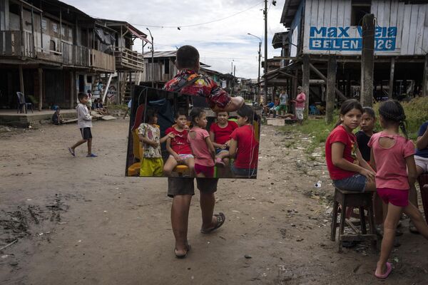 Niños se reflejan en un espejo del vendedor Manolo Apagueno al pasar por el distrito de Belén, en Perú. - Sputnik Mundo