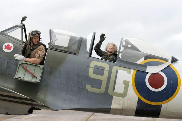 Dorothea Barron, de 99 años, que prestó servicio en el Servicio Naval Real Femenino británico durante la Segunda Guerra Mundial, se sienta en un caza Spitfire con el piloto Jeremy Britcher en el aeropuerto de Biggin Hill en Kent, el Reino Unido. - Sputnik Mundo