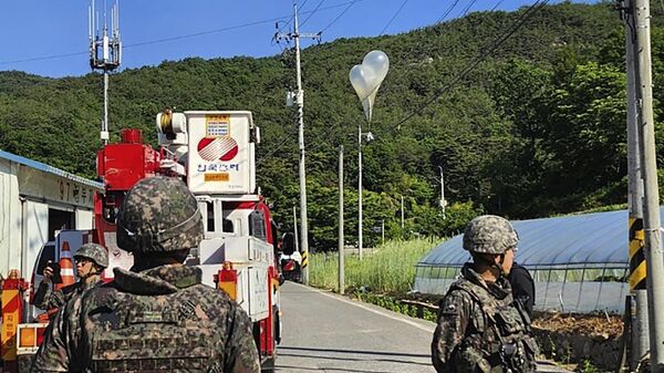 Globos con basura presumiblemente enviados por Corea del Norte, cuelgan de cables eléctricos mientras soldados del Ejército surcoreano montan guardia en Muju, Corea del Sur, el miércoles 29 de mayo de 2024 - Sputnik Mundo