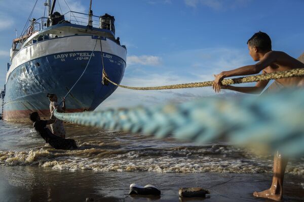 Niños jugando con las cuerdas de un barco amarrado en una playa de Parika, Guyana. - Sputnik Mundo