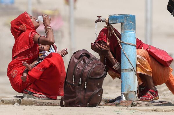 Mujeres beben agua en un caluroso día durante una ola de calor en Prayagraj, India. - Sputnik Mundo