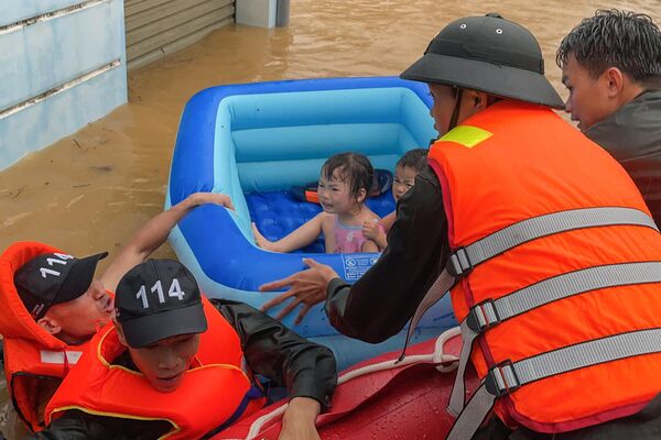 Un equipo de rescate ayuda a unos niños en una barca hinchable a escapar de las aguas tras las fuertes lluvias caídas en la provincia vietnamita de Ha Giang. - Sputnik Mundo
