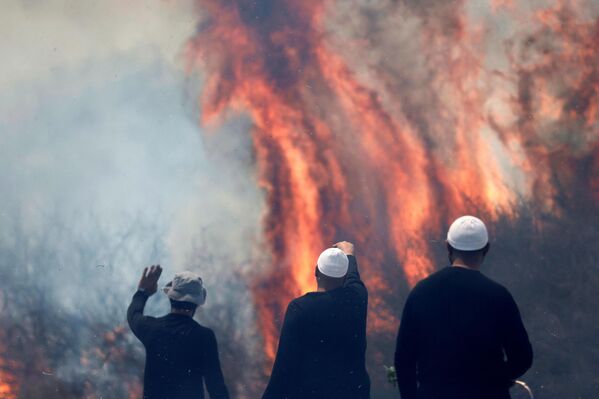 Drusos locales, un grupo étnico-religioso de árabes, observan un incendio tras la caída de cohetes libaneses en el barrio de Banias, Israel. - Sputnik Mundo