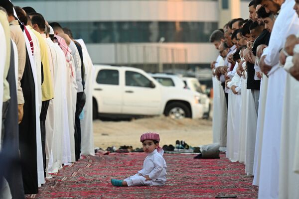 Un niño sentado entre los hombres que realizan la oración de la mañana en la ciudad de Kuwait, en el primer día de la fiesta de Eid al Adha que marca el final de la peregrinación hajj a La Meca. - Sputnik Mundo
