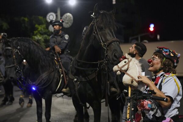 La payasa Hashoteret Az-Oolay juega con un caballo de la Policía Montada israelí mientras participa en una protesta contra el Gobierno del primer ministro israelí, Benjamín Netanyahu. - Sputnik Mundo