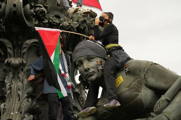 Un manifestante sostiene una bandera palestina en la estatua El Triunfo de la República en París. - Sputnik Mundo