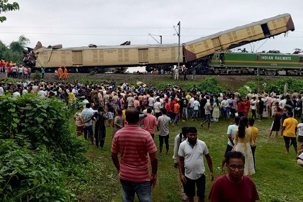 Varias personas observan el lugar de una colisión entre un tren expreso de pasajeros y un tren de mercancías en Nirmaljote, en el estado indio de Bengala Occidental. El 17 de junio, al menos siete personas murieron tras el choque de trenes. - Sputnik Mundo