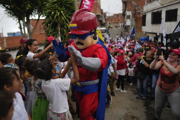 Un hombre vestido como la versión de superhéroe del presidente venezolano, Nicolás Maduro, choca los cinco con niños en una manifestación progubernamental contra las sanciones de EEUU a Venezuela. - Sputnik Mundo
