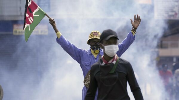 Un manifestante antigubernamental ondea una bandera keniana mientras la policía dispara gases lacrimógenos, el 25 de junio de 2024 - Sputnik Mundo