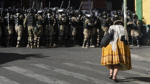 Una mujer pasa junto a policías militares en la Plaza Murillo en La Paz, Bolivia. - Sputnik Mundo