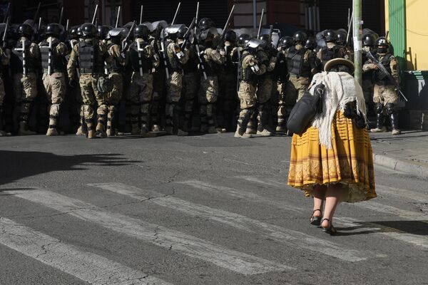 Vehículos blindados embistieron las puertas del palacio de Gobierno de Bolivia, ubicado en la Plaza Murillo, cuando Arce señaló que el país enfrentaba un intento de toma de poder.En la foto: una mujer camina al lado de los militares.  - Sputnik Mundo