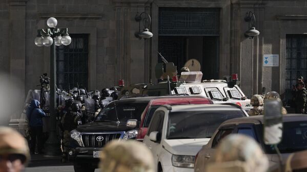 La Policía militar se reúne frente a la entrada principal mientras un vehículo blindado embiste la puerta del palacio del Gobierno.  - Sputnik Mundo