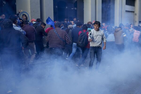 Seguidores del Gobierno actual del país ingresan a la Plaza Murillo mientras policías lanzan gases lacrimógenos.  - Sputnik Mundo