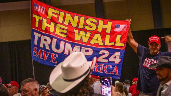 Un simpatizante de Donald Trump sostiene un cartel que dice: Acaba el muro. Trump 24, salvar a América - Sputnik Mundo