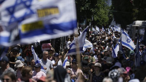 Manifestantes marchan con banderas israelíes durante una protesta para conmemorar los nueve meses transcurridos desde el comienzo del conflicto palestino-israelí y pedir la liberación de los rehenes retenidos en la Franja de Gaza por el movimiento Hamás, el 7 de julio, 2024 - Sputnik Mundo