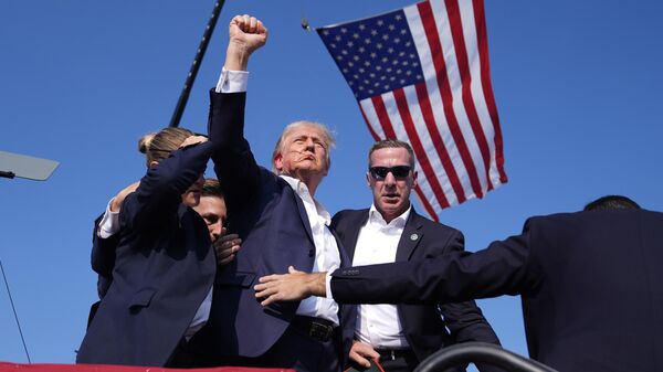 El candidato presidencial republicano, el expresidente Donald Trump, gesticula mientras es rodeado por agentes del Servicio Secreto de EEUU tras el atentado en su contra, el 13 de julio del 2024 - Sputnik Mundo