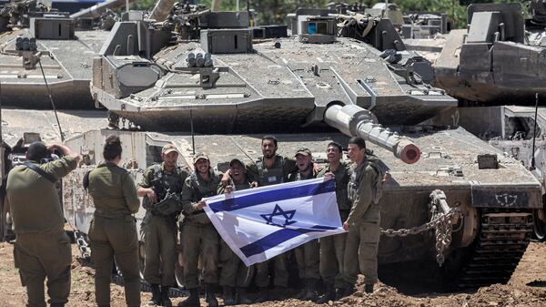 Soldados israelíes sostienen una bandera de su país en la frontera con la Franja de Gaza - Sputnik Mundo