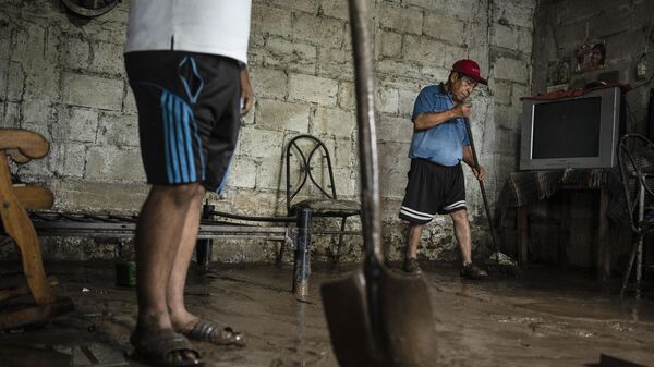 Un hombre y su hijo limpian su casa, que fue afectada por el desbordamiento del río Actopan en Veracruz, México, el lunes 1 de julio de 2024 (imagen referencial) - Sputnik Mundo