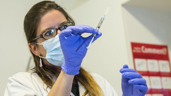 A nurse holds a dose of experimental vaccine cAd3-EBOZ Lau - Sputnik Mundo