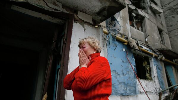 A woman reacts as she stands near a multi-storey block of flats damaged by shelling in Yenakieve town, northeast from Donetsk, February 2, 2015 - Sputnik Mundo