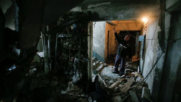 A man shows a staircase at a multi-storey block of flats damaged by shelling in Yenakieve town, northeast from Donetsk, February 2, 2015 - Sputnik Mundo