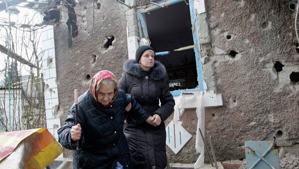 People walk outside a house damaged by shelling in Donetsk - Sputnik Mundo