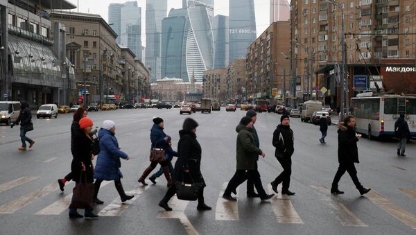 People cross the road as the buildings of the Moscow International Business Center are seen in the background - Sputnik Mundo