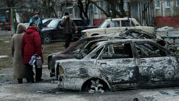 People look at burned out cars as they walk along a street in the southern Ukrainian city of Mariupol - Sputnik Mundo