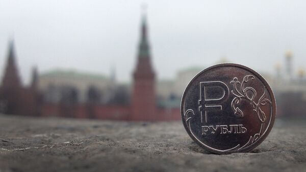 A Russian ruble coin is pictured in front of the Kremlin in in central Moscow, on November 6, 2014 - Sputnik Mundo