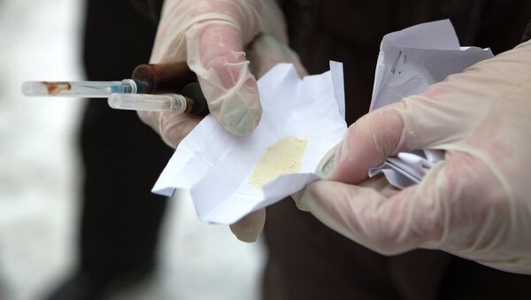 Un policía del departamento de narcóticos sostiene en la mano dos jeringuillas y una dosis de heroína (archivo) - Sputnik Mundo