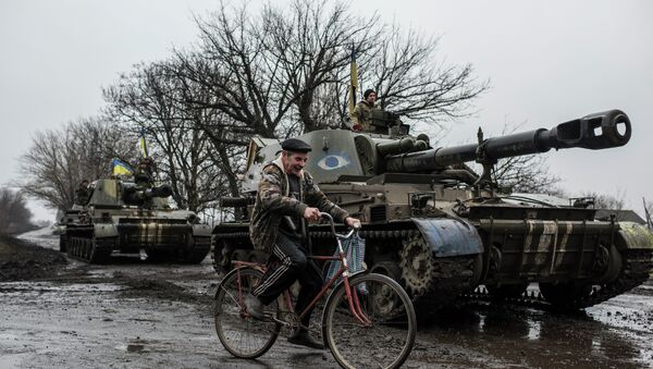 A local resident rides a bicycle as Ukrainian servicemen sit atop an armoured vehicle with Ukrainian flags, on the outskirts of Donetsk, Ukraine, Wednesday, March 4, 2015 - Sputnik Mundo