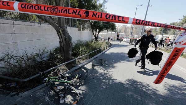 An Israeli policeman, holding bags belonging to pedestrians injured during an attack, walks past a bicycle damaged during the attack in Jerusalem March 6, 2015 - Sputnik Mundo