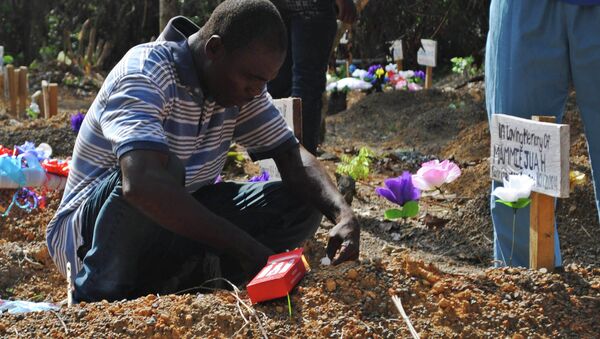 Sobreviviente del virus Ébola llora en la tumba de su hijo en un cementerio para las víctimas de Ébola - Sputnik Mundo