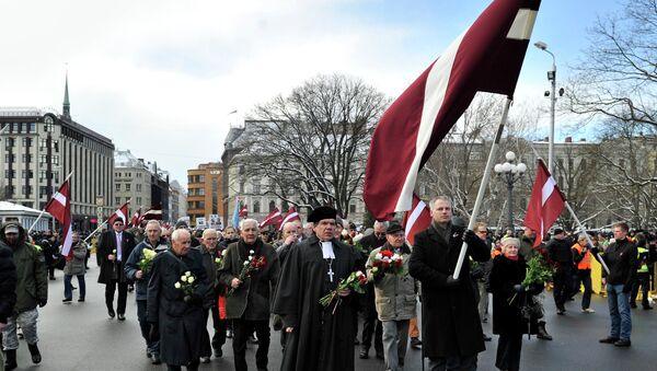 People carry Latvian flags as they march to the Freedom Monument to commemorate World War II veterans who fought in Waffen SS divisions, in Riga, Latvia, Sunday, March 16, 2014 - Sputnik Mundo