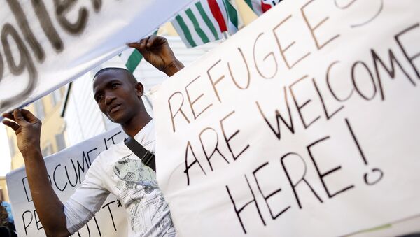 A migrant holds a placard during a protest in front of the Italian Chamber of Deputies in Rome - Sputnik Mundo