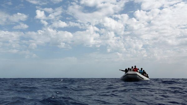 A group of 106 sub-Saharan Africans on board a rubber dinghy wait to be rescued by the NGO Migrant Offshore Aid Station some 25 miles off the Libyan coast, in this October 4, 2014 - Sputnik Mundo