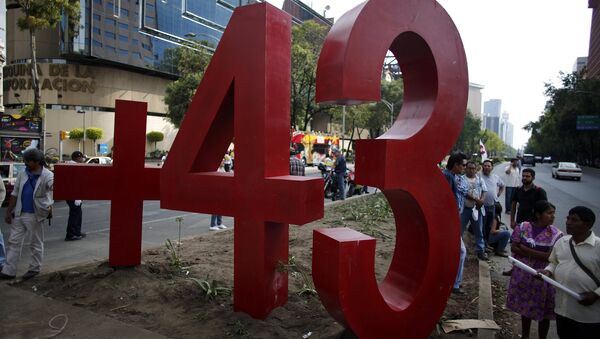 People stand next to a monument of the number 43 during a protest to mark the seven months of the Ayotzinapa students' disappearance in Mexico City  - Sputnik Mundo