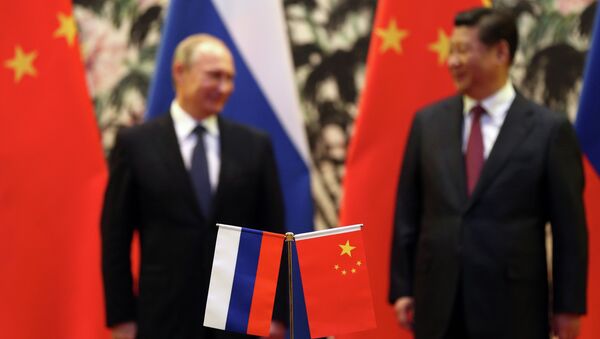 The Russian and Chinese national flags are seen on the table as Russia's President Vladimir Putin (back L) and his China's President Xi Jinping (back R) stand during a signing ceremony at the Diaoyutai State Guesthouse in Beijing on November 9, 2014 - Sputnik Mundo