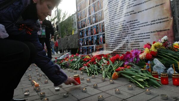 Mujer enciende una vela a los retratos de los muertos en el incendio en la Casa de Sindicatos en Odesa - Sputnik Mundo