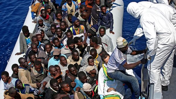Migrants crowd and inflatable dinghy as rescue vassel  Denaro  of the Italian Coast Guard approaches them, off the Libyan coast, in the Mediterranean Sea, Wednesday, April 22, 2015 - Sputnik Mundo
