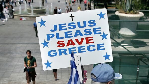 Un hombre lleva una bandera griega y una pancarta que dice Jesús, salva, por favor, a Grecia - Sputnik Mundo