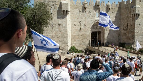 Israeli youths hold their national flag as they take part in the flag march through Damascus Gate in Jerusalem's old city during celebrations for Jerusalem Day on May 17, 2015 - Sputnik Mundo