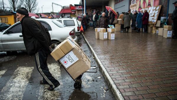 A man drags a trolley with aid as he leaves a Red Cross distribution center in Debaltseve - Sputnik Mundo